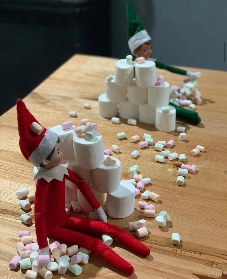 two elfs are sitting on the table with marshmallows all over them