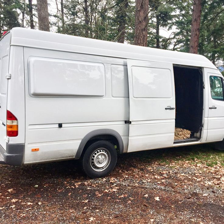 a white van parked in the woods with its door open and food inside it's compartment