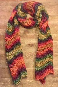 a multicolored knitted scarf sitting on top of a wooden floor