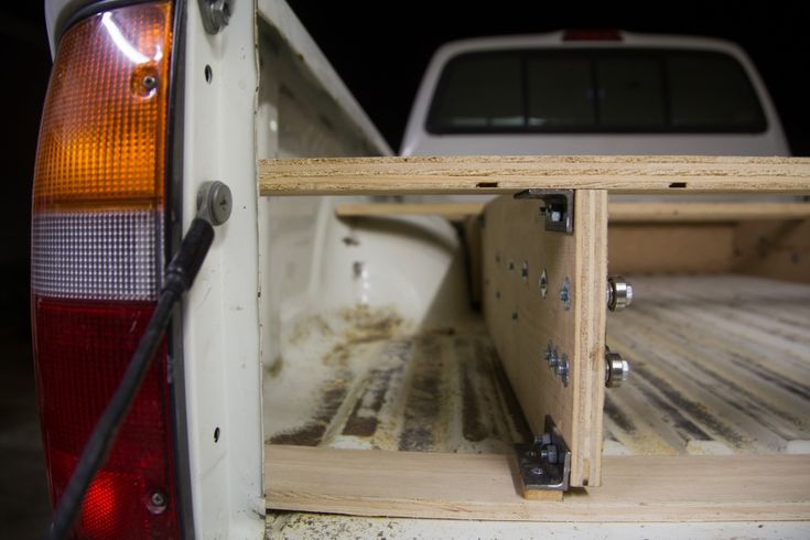 the back end of a white pickup truck with wood in it's bed area