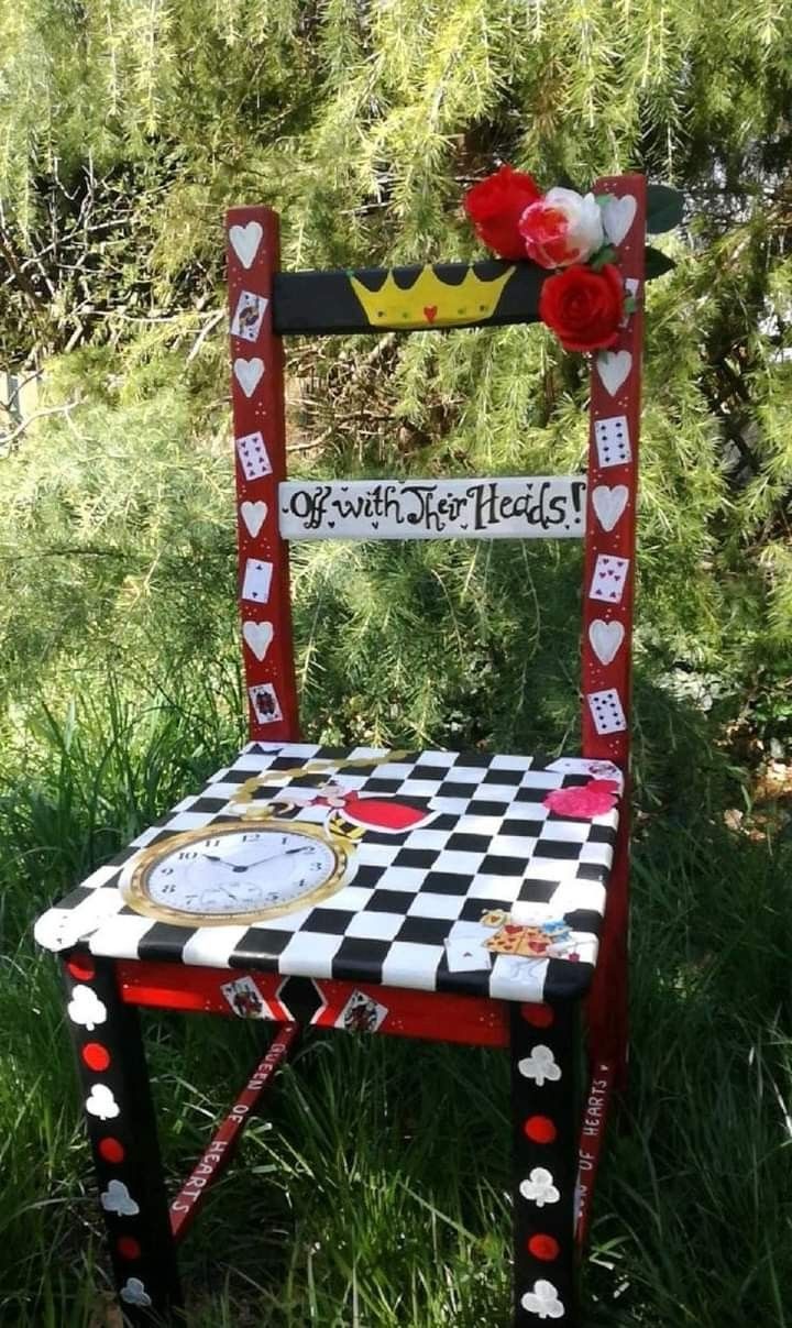 an old chair decorated with hearts and checkered fabric is sitting in the grass near some trees