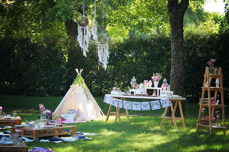 a teepee tent set up in the middle of a field with picnic tables and chairs