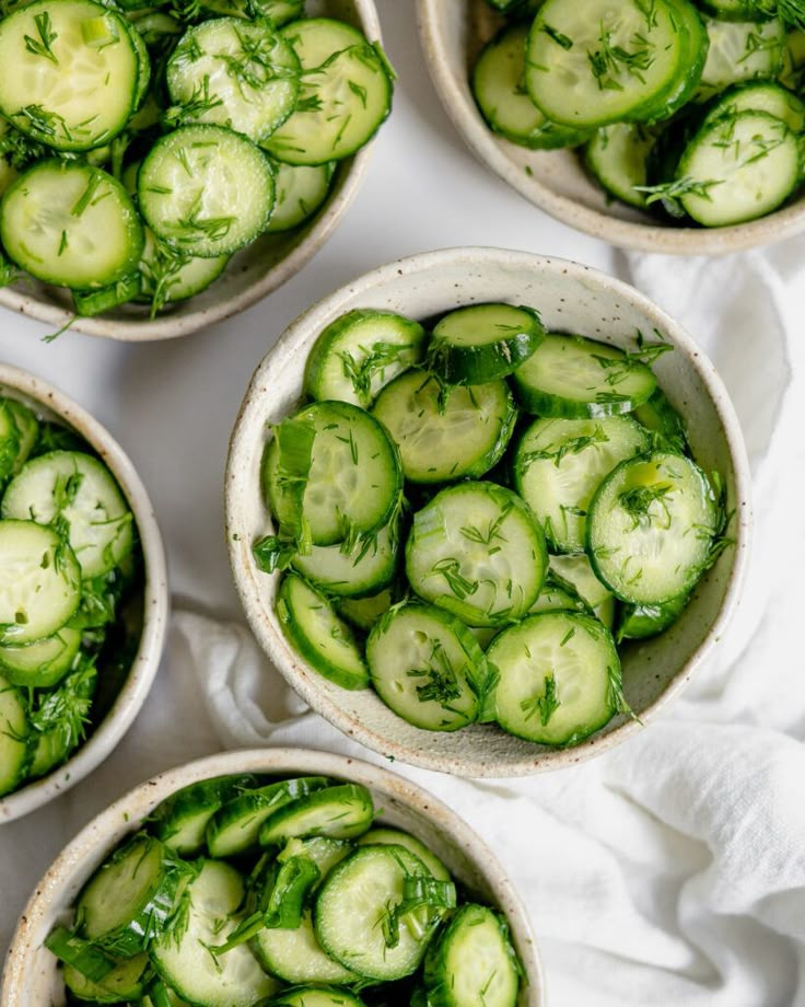 four bowls filled with cucumbers on top of a white cloth