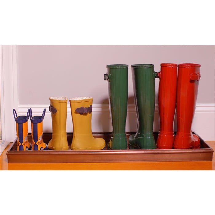 several pairs of colorful rain boots are lined up on a wooden tray in front of a door