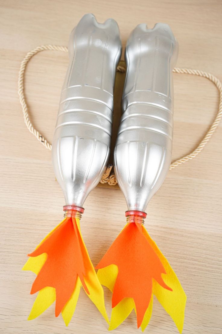 two orange and yellow paper leaves are attached to silver water bottles on a wooden table