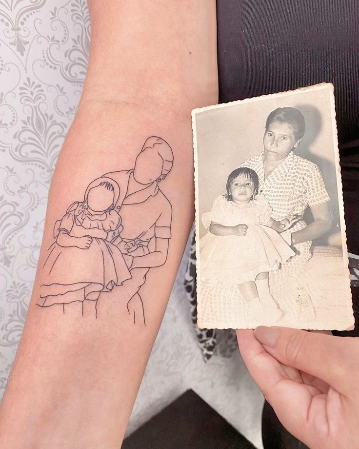 a woman's arm with a drawing of an adult holding a child on it