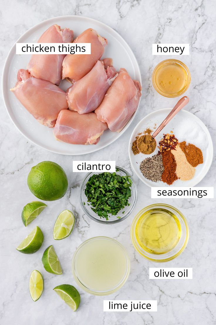 ingredients for chicken thighs on a white plate with limes, seasonings and spices