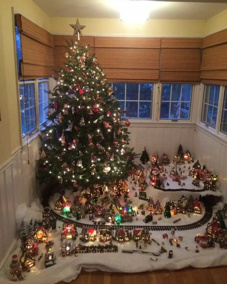 a christmas tree is in the middle of a room with many toys on the floor