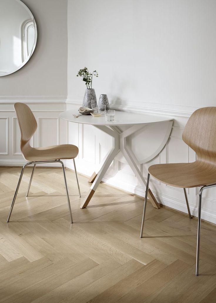 two chairs sitting at a small table in a room with white walls and wood flooring