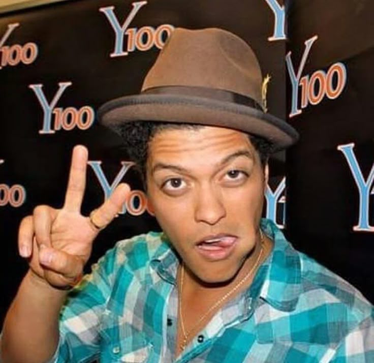 a man with a hat on giving the peace sign in front of a yahoo backdrop