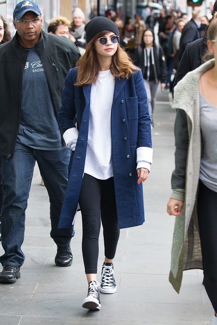 a man and woman walking down the street in front of some people wearing black sneakers