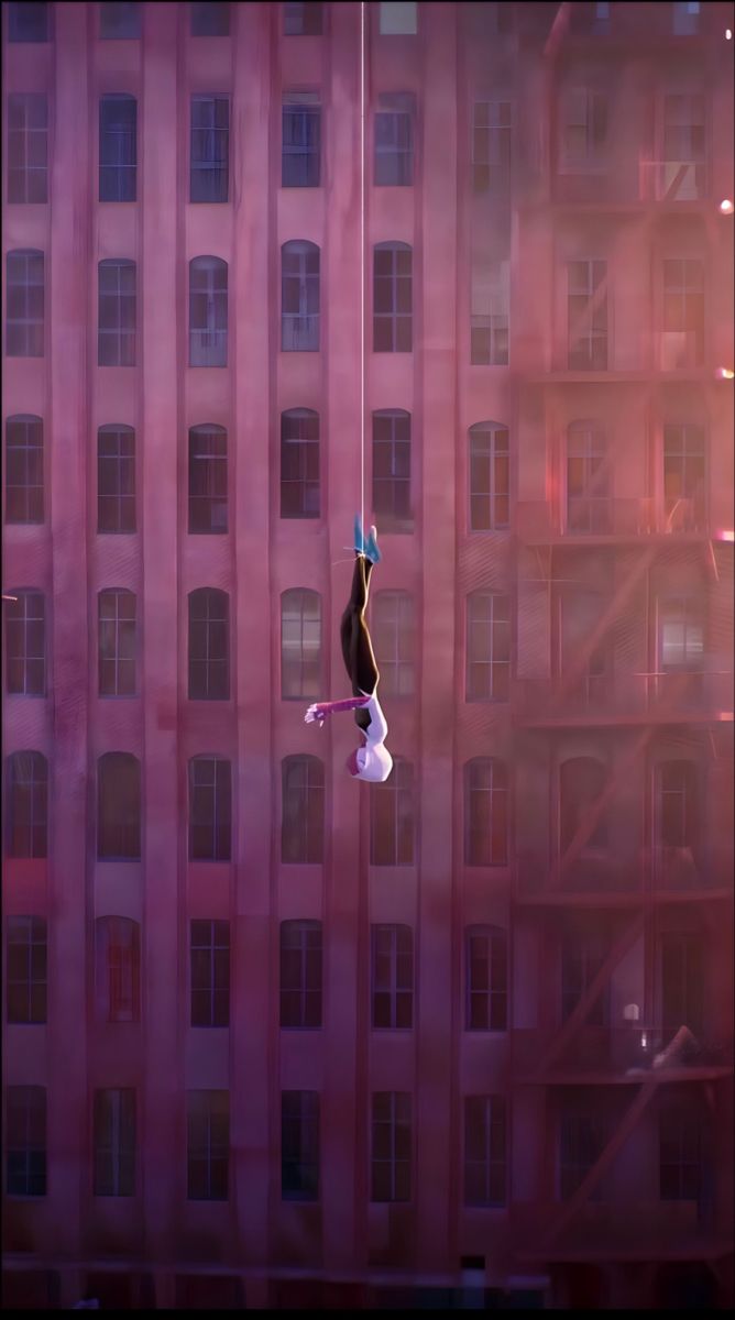 a person hanging upside down from a high rise building in the air with their hands up