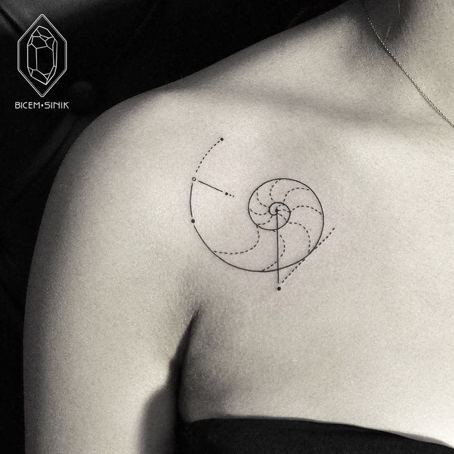 a black and white photo of a woman's shoulder with a tattoo on it