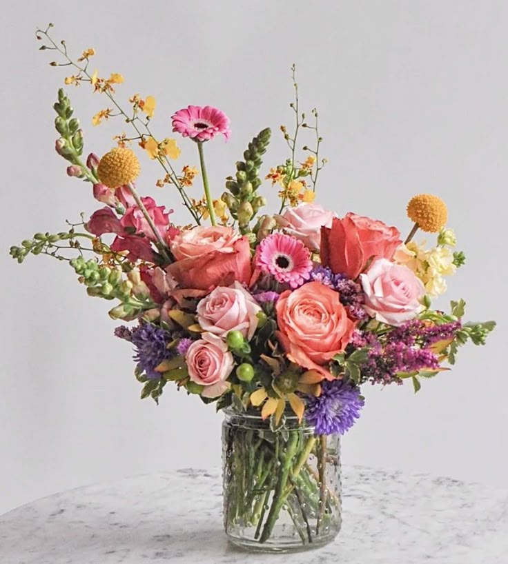 a vase filled with lots of different colored flowers