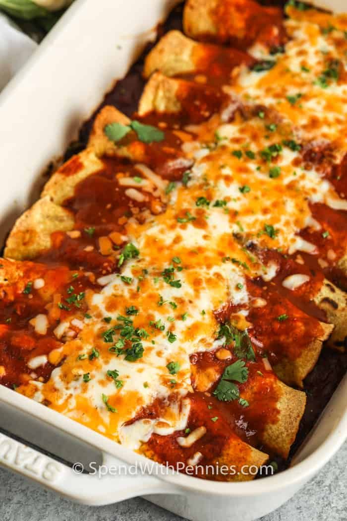 an enchilada casserole with cheese and sauce in a white dish