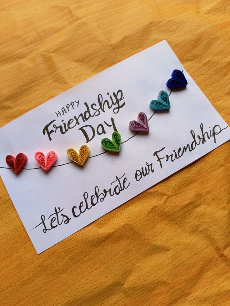 a greeting card with hearts hanging on a string that says happy friends day let's celebrate our friendship