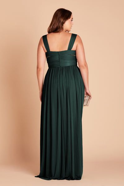 a woman in a dark green dress with her back to the camera, looking down