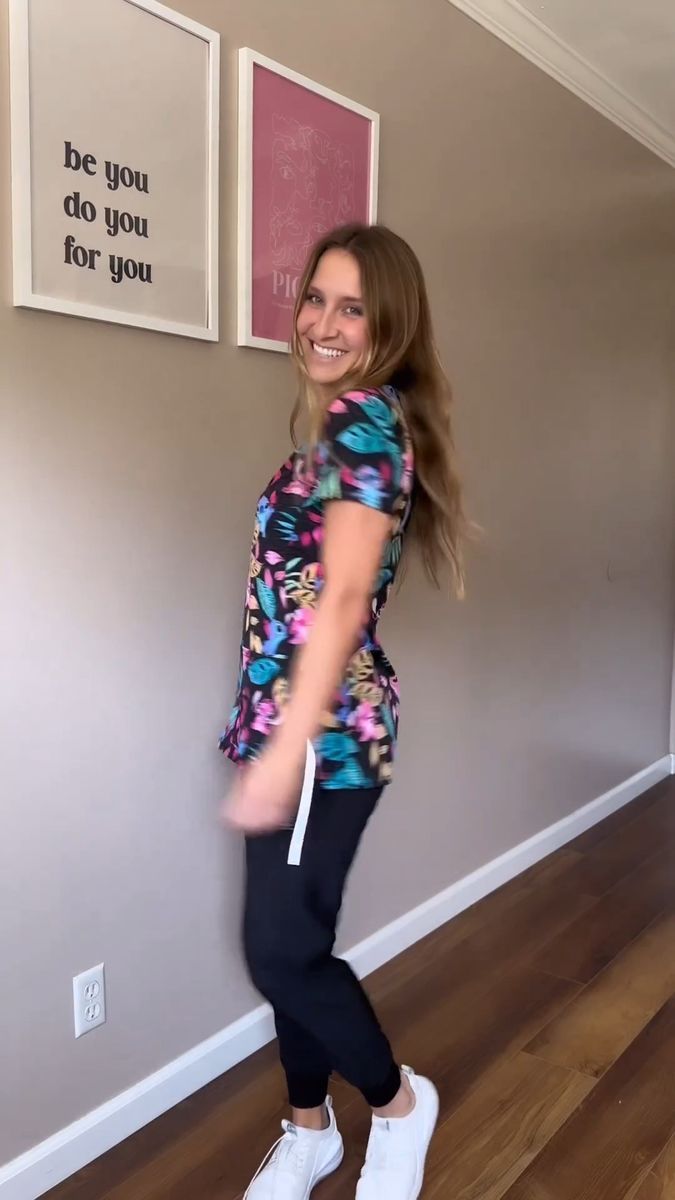 a woman standing in front of a wall with her legs spread out and smiling at the camera