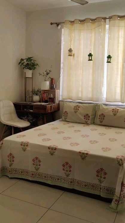 a bed sitting in a bedroom next to a window with curtains on top of it