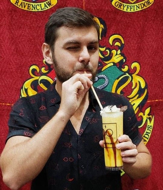 a man holding a drink in front of his mouth and drinking it from a straw