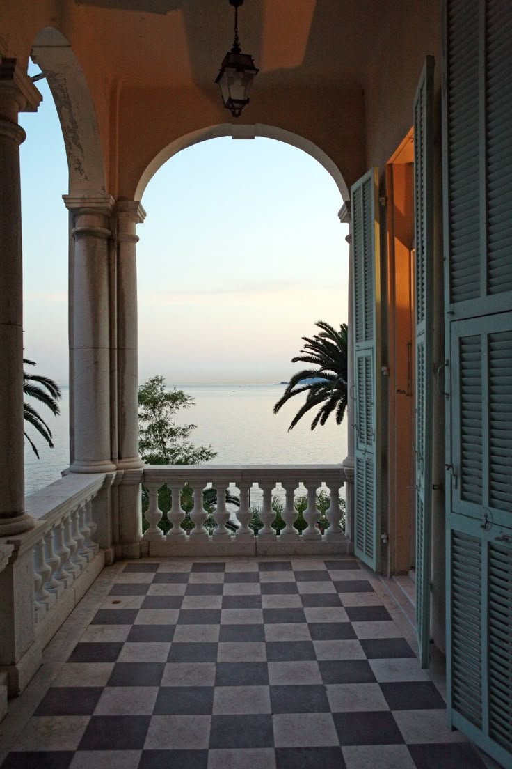 an open porch with checkered tile flooring and columns