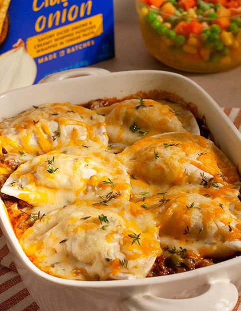 a casserole dish with cheese and vegetables in it next to a box of cheesy potatoes