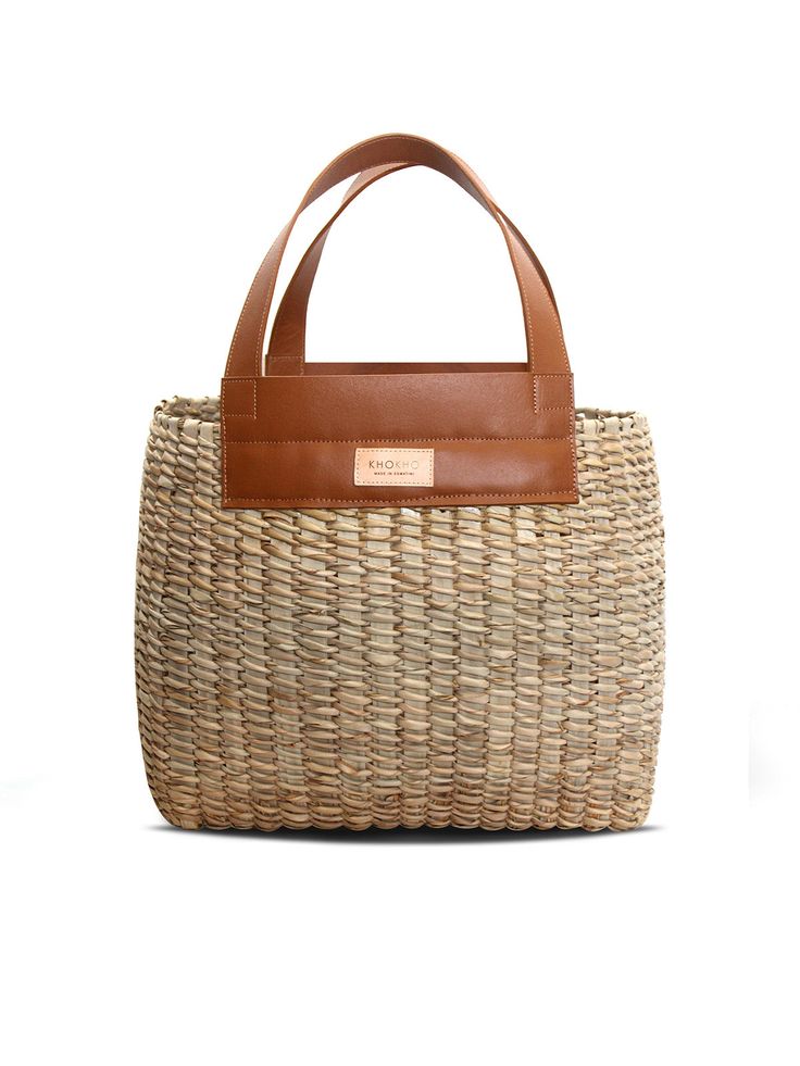 Make even the most relaxed outfits that little bit more chic with this basket bag by Khokho Collection. It’s handwoven by the brand’s all-female team of artisans from locally-sourced natural fibers and finished with tan leather handles and trims. Wear yours with a lightweight linen suit as soon as the weather heats up. - Top handles, open top - Natural fibers, cow leather - Any variations in tone or texture are inherent to the handcrafted nature of each bag - Artisanally crafted by a local femal Chic Handwoven Natural Fiber Bucket Bag, Chic Woven Leather Top Handle Beach Bag, Woven Natural Fiber Basket Bucket Bag, Natural Jute Top Handle Bucket Bag, Chic Jute Straw Bag With Woven Leather, Chic Straw Bag With Woven Leather Details, Woven Basket Bucket Bag In Natural Color, Chic Handwoven Natural Bucket Bag, Natural Woven Basket Bucket Bag