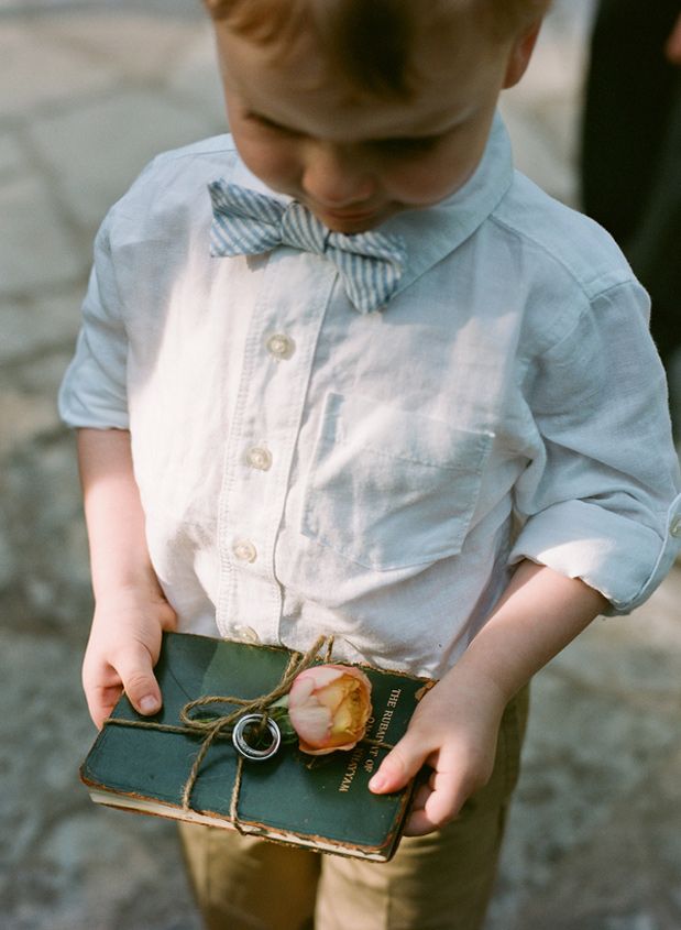 a young boy wearing a bow tie and holding an apple in his hand while standing on the ground