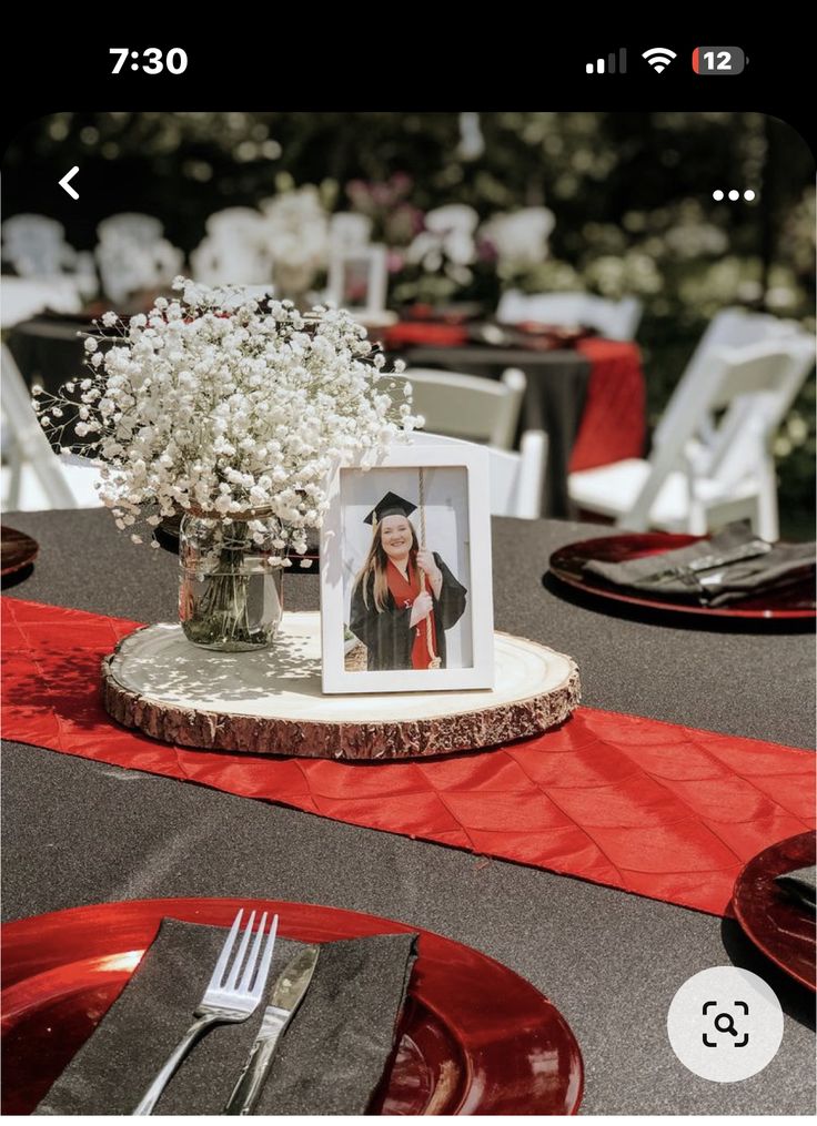 the table is set with red plates, silverware and a photo frame on it