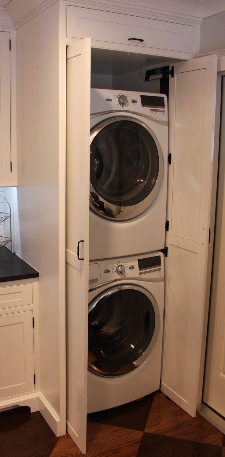 a white washer and dryer in a small room with cabinets on either side