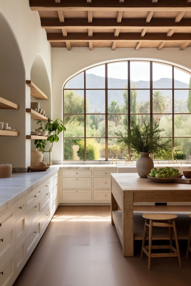 a large kitchen with an arched window and wooden counter tops, along with white cabinets