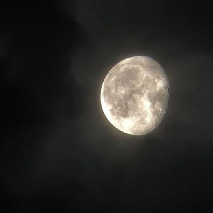 the full moon is seen through dark clouds