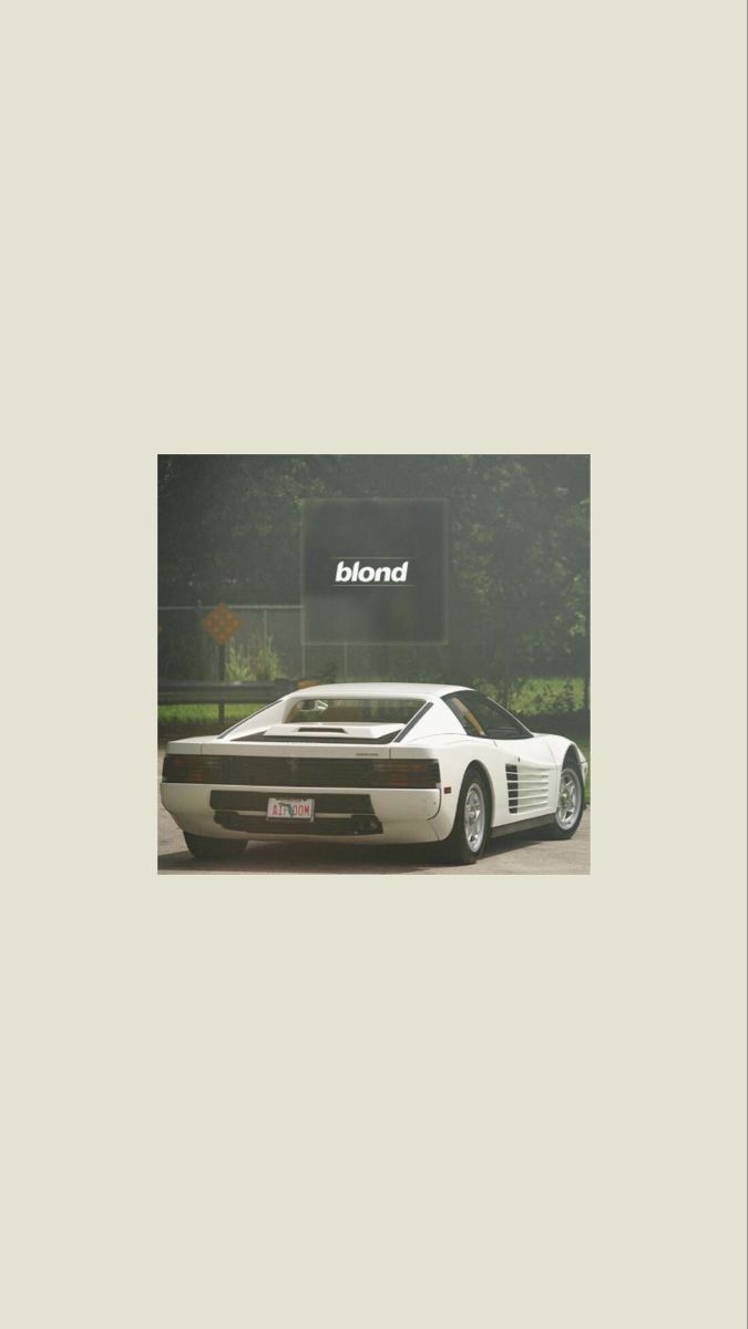 a white sports car is parked in front of a sign that says kondo on it