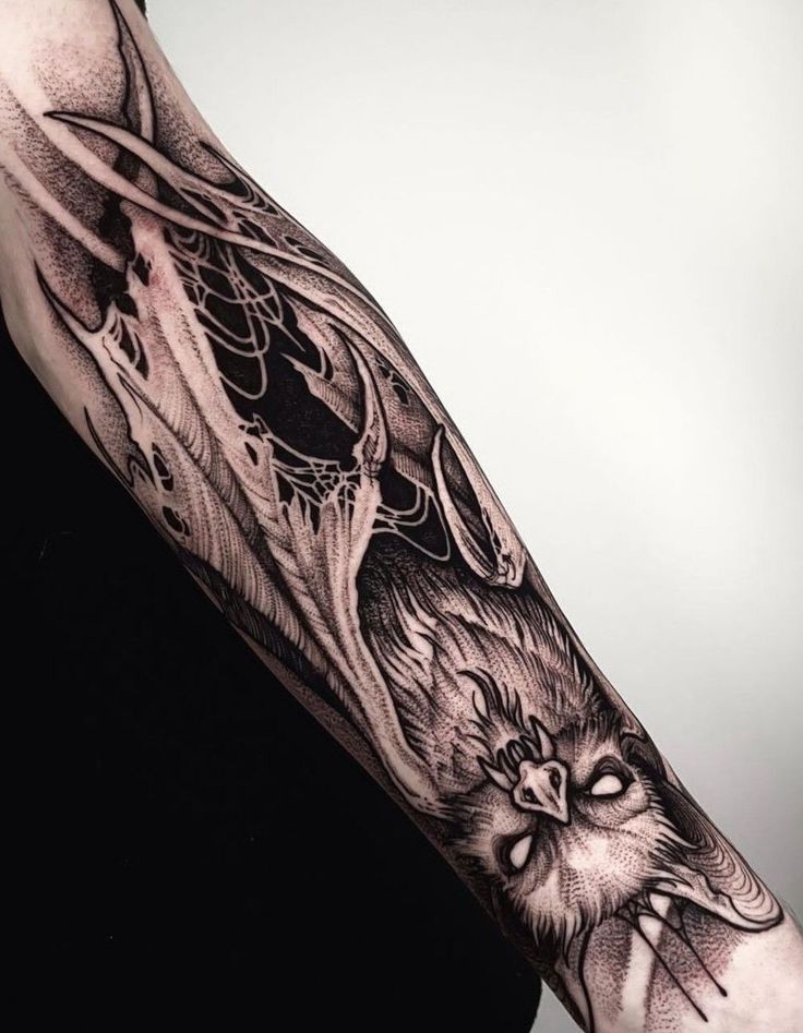 an owl tattoo on the left arm and shoulder is shown in black and grey ink