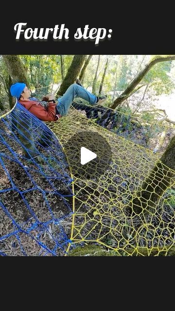 a man laying on top of a blue net in the woods