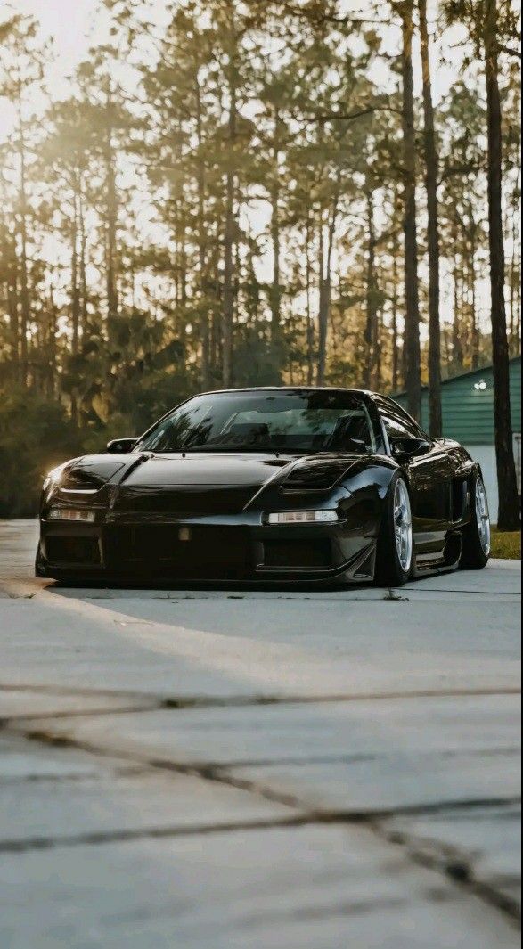 a black sports car parked in front of some trees