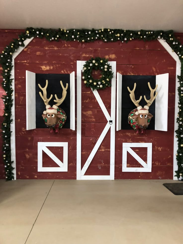 two deer heads are mounted to the side of a barn door decorated with christmas decorations