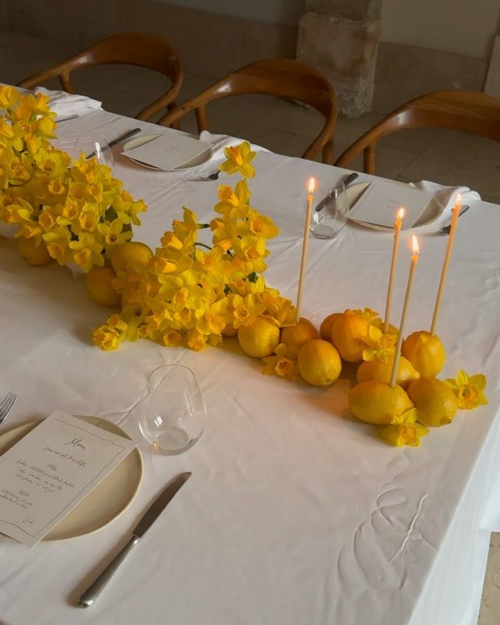 the table is set with yellow flowers and candles