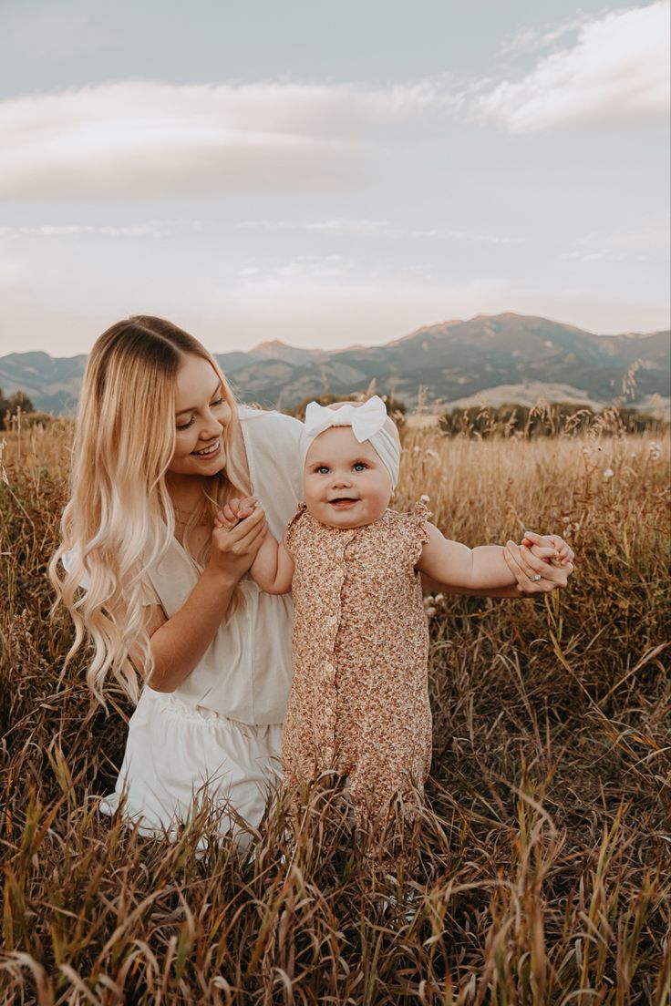 a woman holding a baby in a field