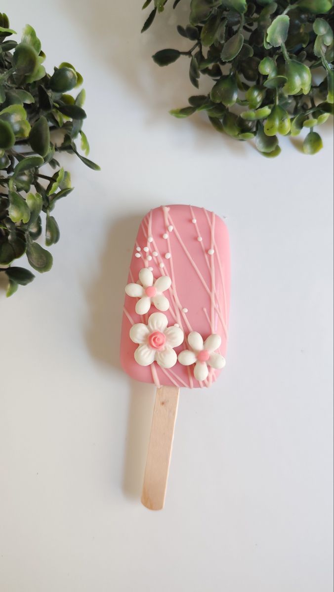 an ice cream popsicle decorated with pink icing and white sprinkles