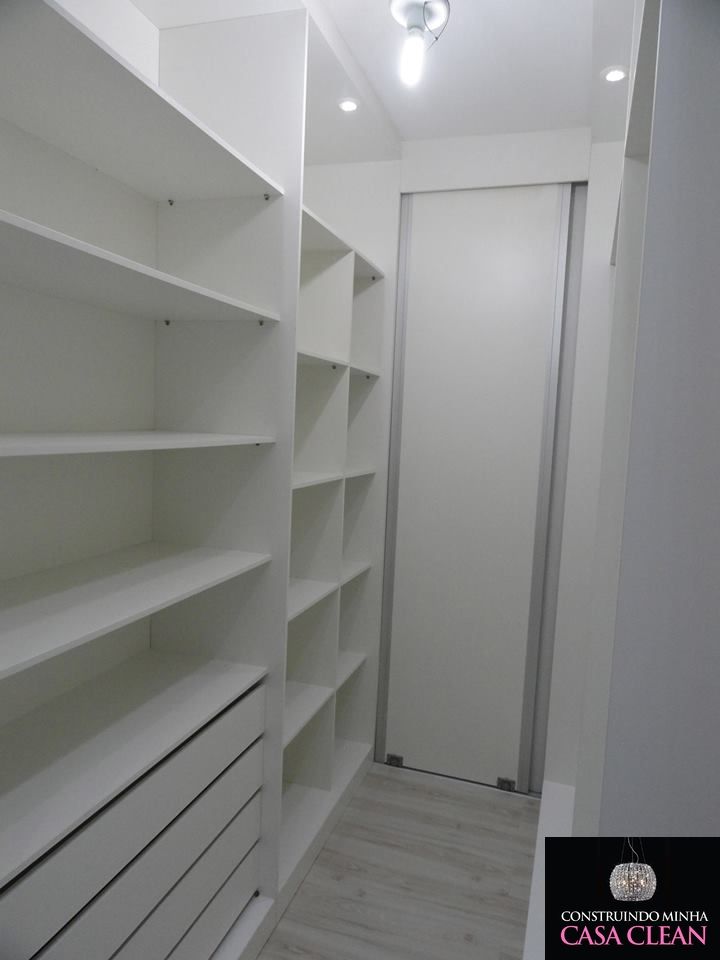 an empty walk in closet with white shelving