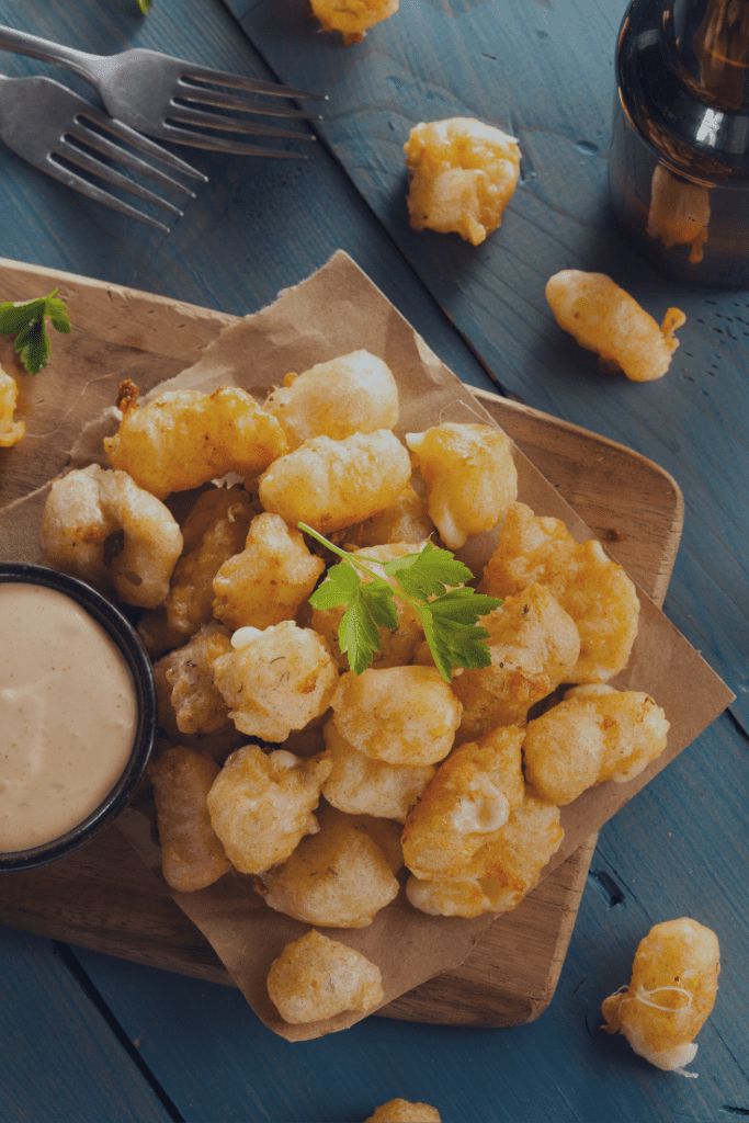 some fried food is sitting on a plate with a dipping sauce in the middle and garnished with parsley