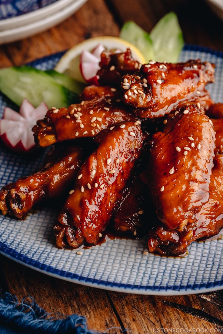 chicken wings with sesame seeds and garnishes on a blue plate