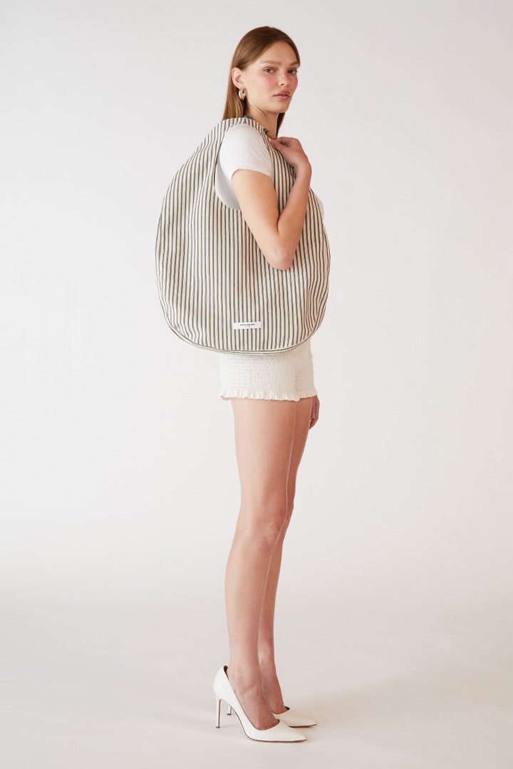 The Stripe Egg Tote Bag is a unique and functional accessory made from durable cotton canvas in NYC. Its distinctive egg-shaped design provides ample space while maintaining a sleek profile. Available in red and cream stripe or classic black and cream stripe, the Strip Egg Tote Bag combines practicality with a contemporary look. Orseund Iris offers a 14-day exchange & return policy for all items except for final sale pieces. Beige Tote Shoulder Bag With Striped Lining, Chic Shoulder Bag With Striped Lining, Chic Shoulder Bag With Striped Lining For Everyday, Casual Beige Bag With Striped Lining, Modern Striped Tote Bag, Canvas Bags With Striped Lining For Everyday Use, Everyday Striped Bag With Adjustable Strap, Everyday Striped Shoulder Bag With Adjustable Strap, Everyday Use Shoulder Bag With Striped Lining