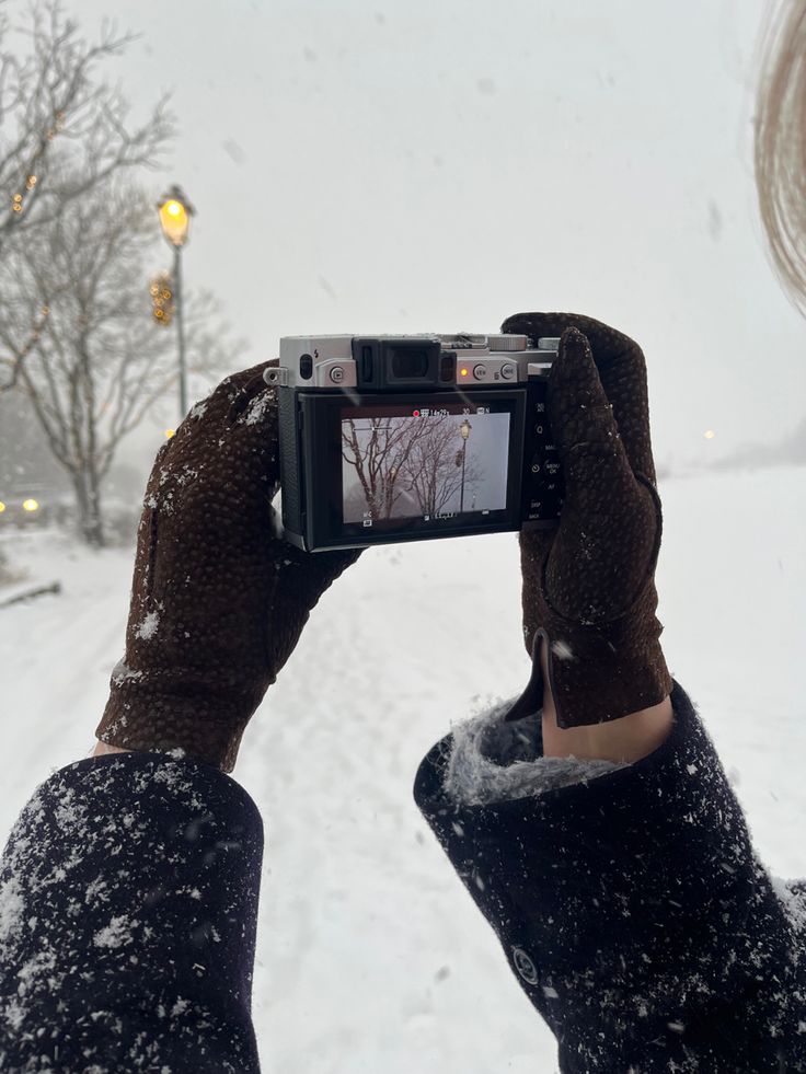 a person holding up a camera in the snow