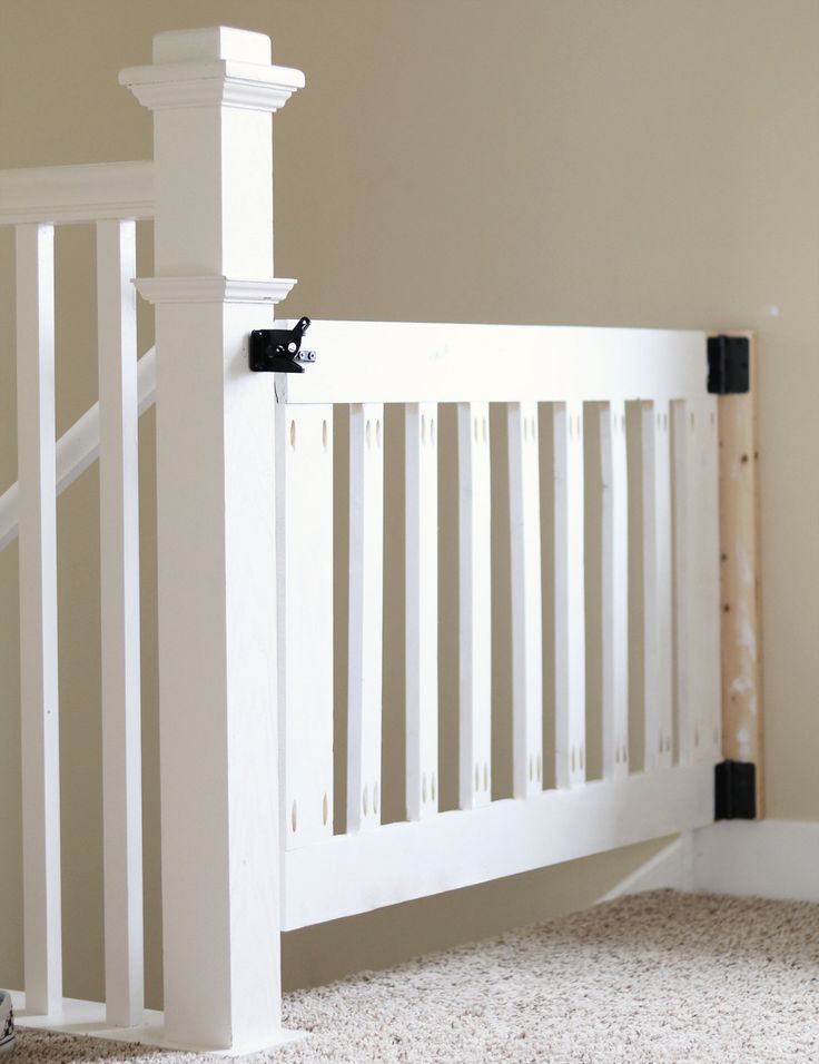 a close up of a white railing in a room with carpeted floor and walls