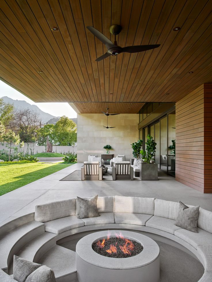 a fire pit sitting in the middle of a patio next to a wooden ceiling fan