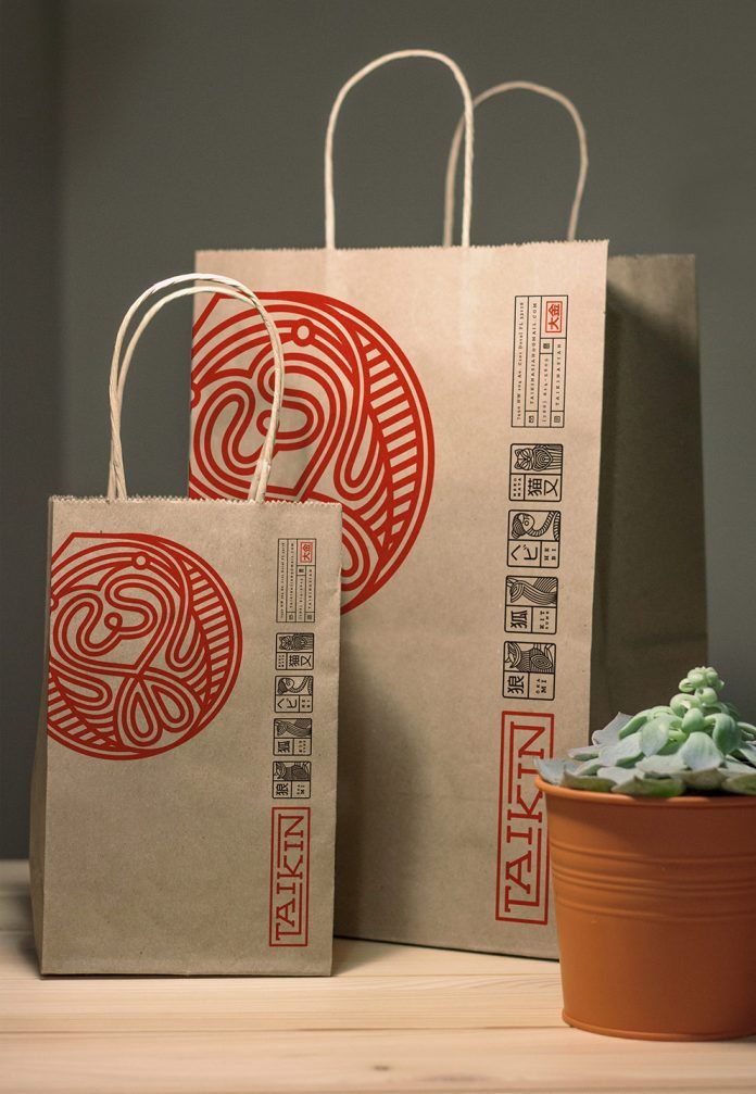 two brown bags sitting on top of a wooden table next to a potted plant