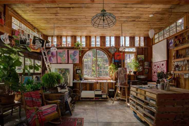 a room filled with lots of wooden furniture and plants on the wall next to windows