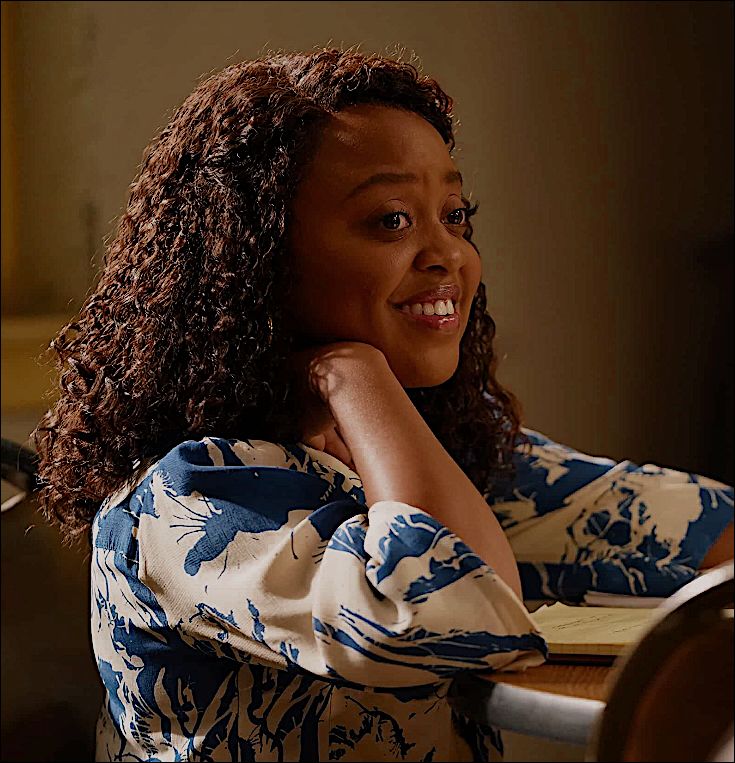 a woman with curly hair sitting at a table